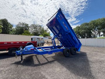 Blue dump trailer raised on a sunny day.