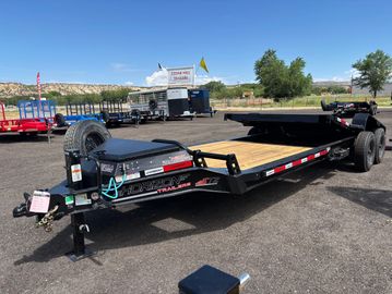 Black flatbed trailer parked in an outdoor lot.