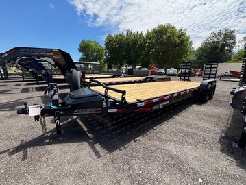 Flatbed trailer parked on gravel under blue sky.