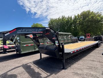 Black Horizon trailer with a wooden deck under a blue sky.