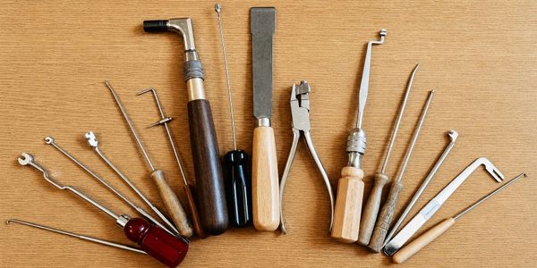 A collection of various hand tools arranged on a wooden surface.