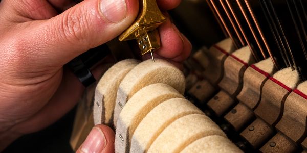 Close-up of piano tuning with a tuning tool and felt hammers.