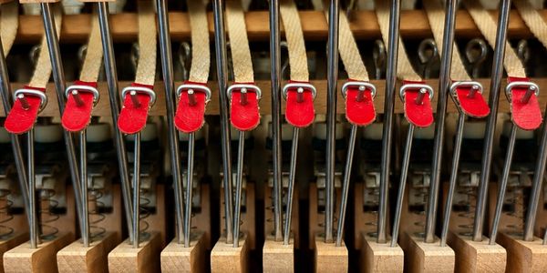Close-up of piano hammers with red felt tips inside the instrument.