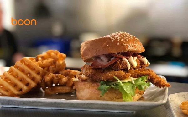 Crispy chicken sandwich with waffle fries on a tray.