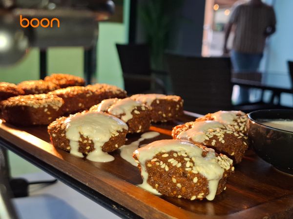 Sesame-coated fried snacks with creamy sauce on a wooden tray.