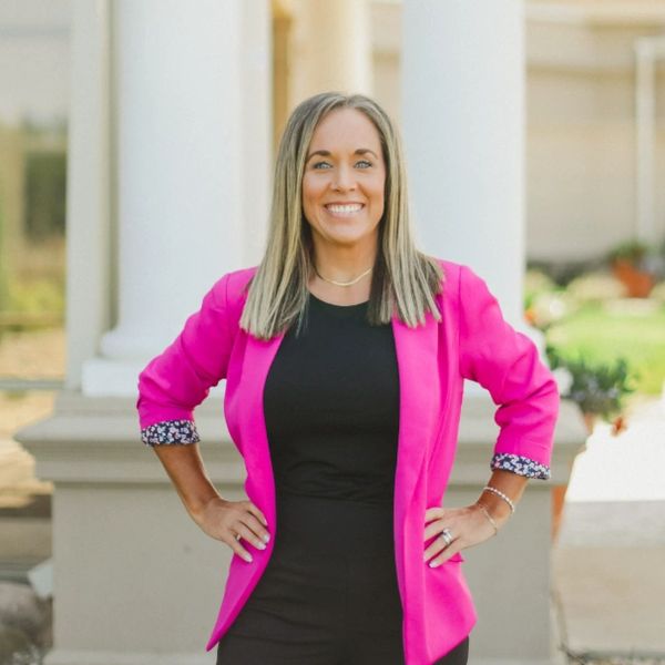 Woman smiling confidently in a pink blazer.