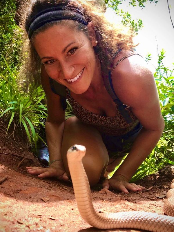 A woman smiling and observing a snake closely.