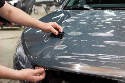 Person inspecting car with water spots.