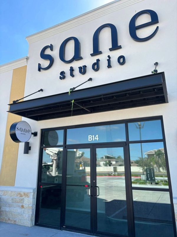 Entrance of Sane Studio with black letters and glass doors.