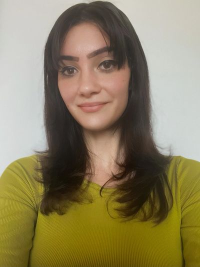 Young woman with dark hair in a green top smiling gently at the camera.