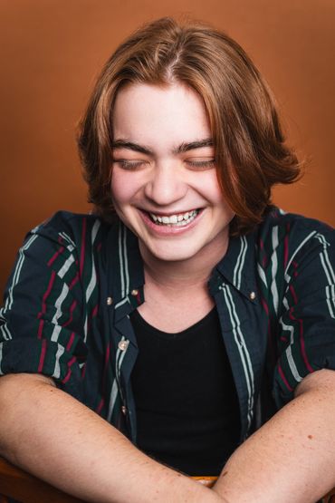 A person with long hair and a shirt smiling.
