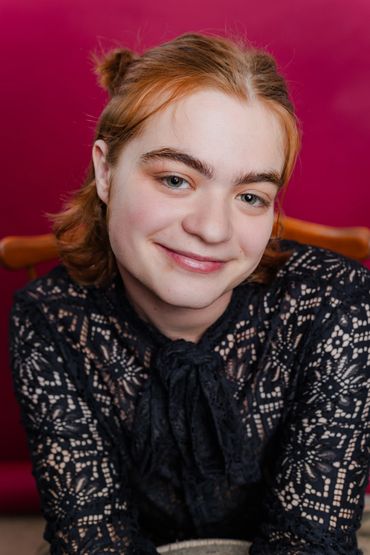 A woman with red hair and black lace shirt.