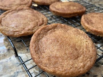 Freshly baked, round cookies cooling on a wire rack.