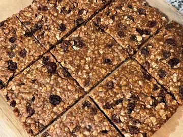 Freshly baked oatmeal raisin bars cut into squares on a wooden board.