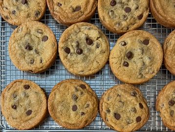 Freshly baked chocolate chip cookies cooling on a wire rack.