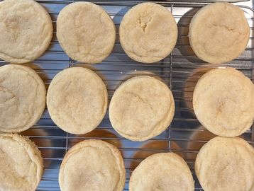 Twelve freshly baked cookies cooling on a wire rack.