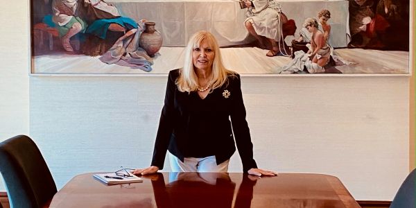 Woman standing behind a wooden table in a formal setting.