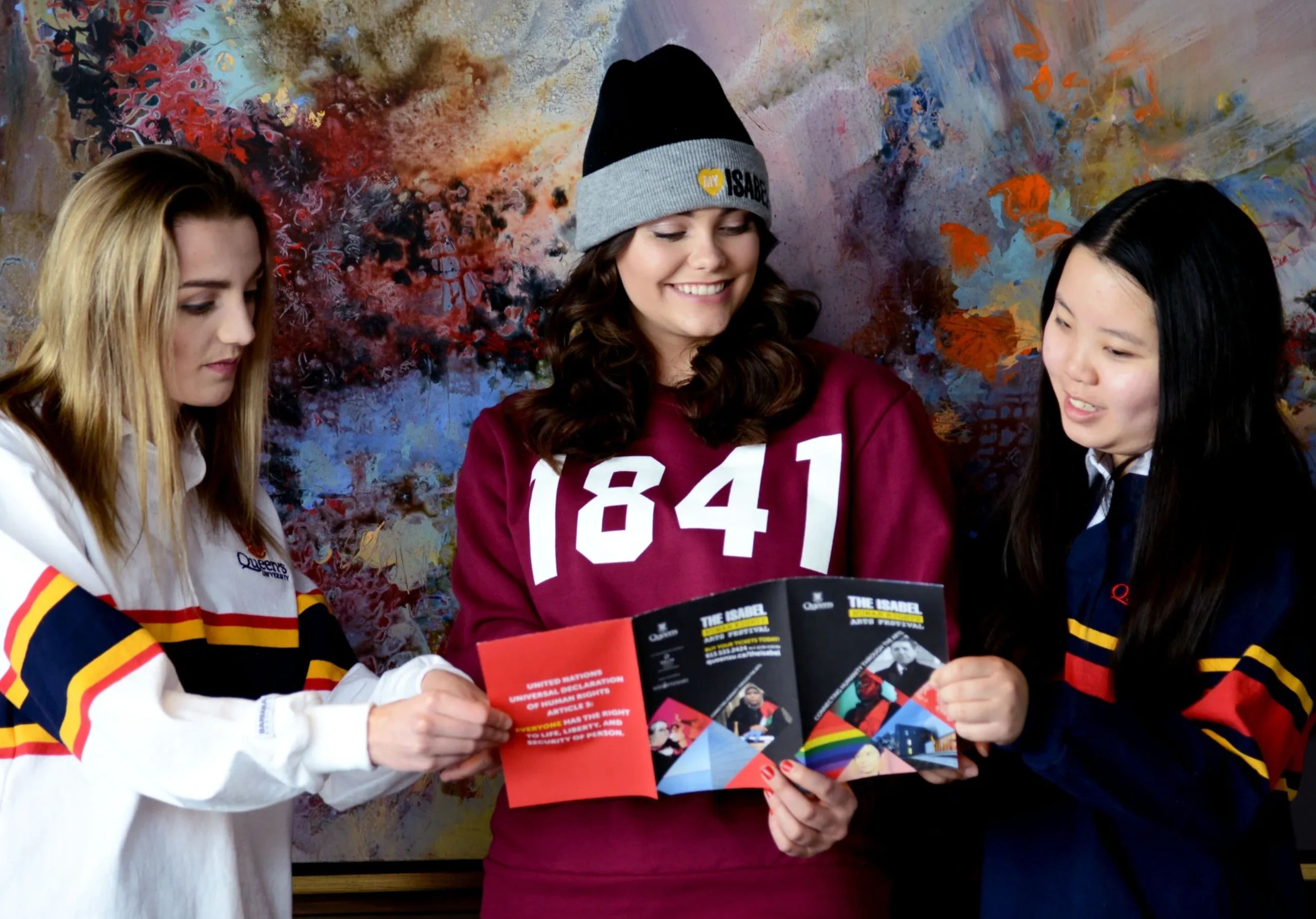 Group of people smiling and looking at brochure in front of an abstract painting.