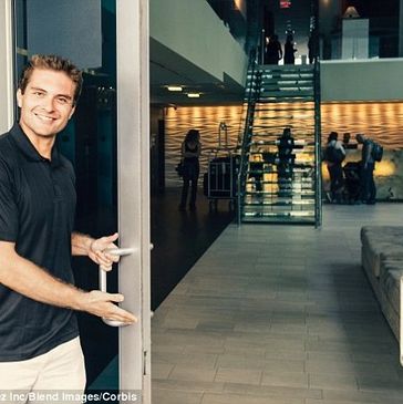 Smiling man holding open a door, inviting people inside.