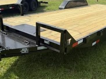 Flatbed trailer with wooden deck parked on grass.
