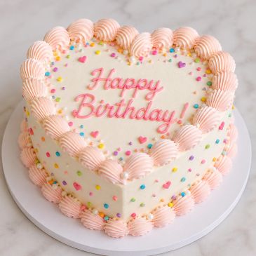 Heart-shaped birthday cake with pink frosting.