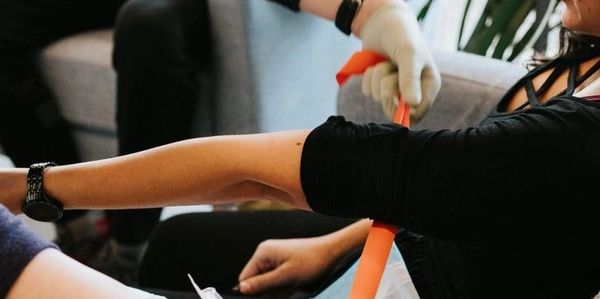 Person preparing for blood draw with tourniquet on arm.