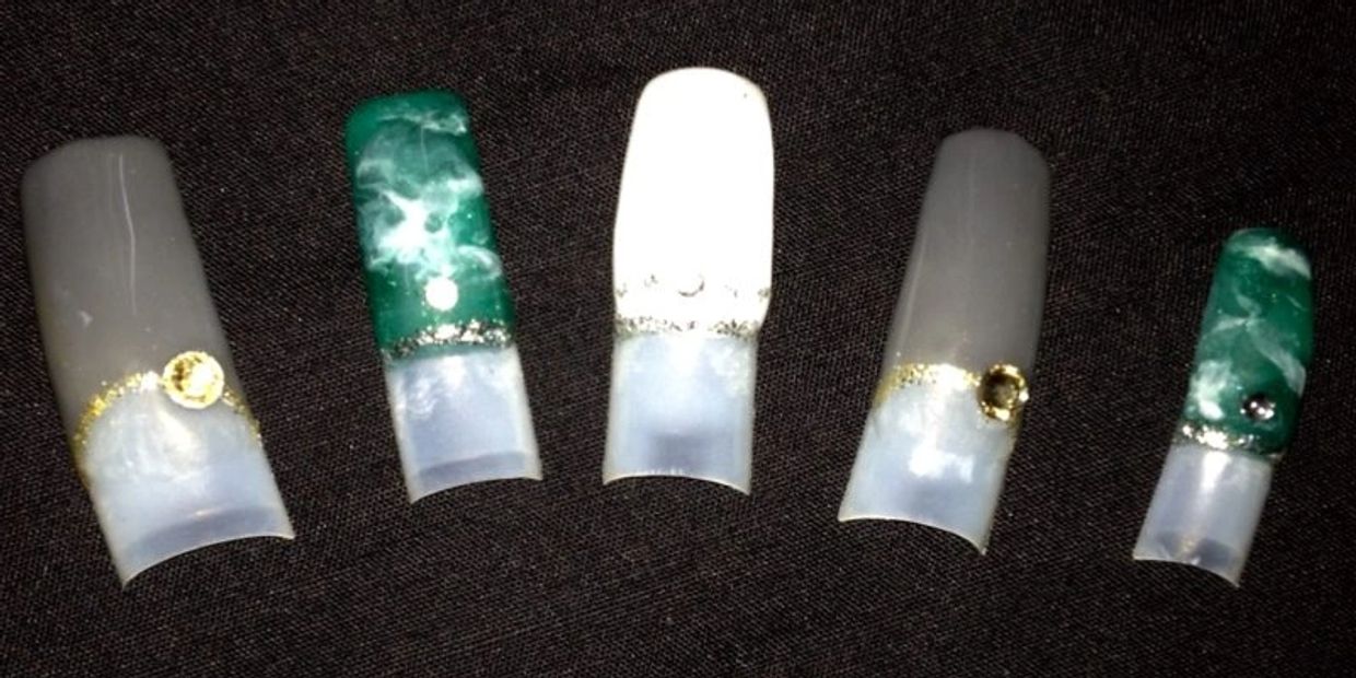Set of decorative artificial nails with green, white, and gold accents.