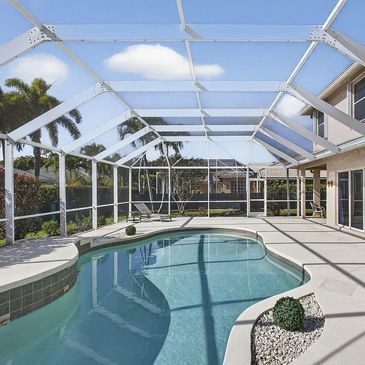 Clear blue swimming pool in enclosed patio with lounge chairs.