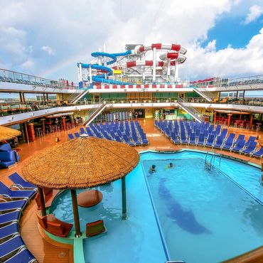 Pool on Carnival Horizon with waterpark in the background.