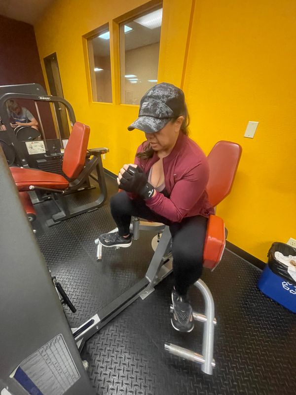 Woman working out on a gym machine in a yellow-walled room.