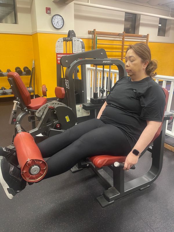 A woman using a leg extension machine in a gym.