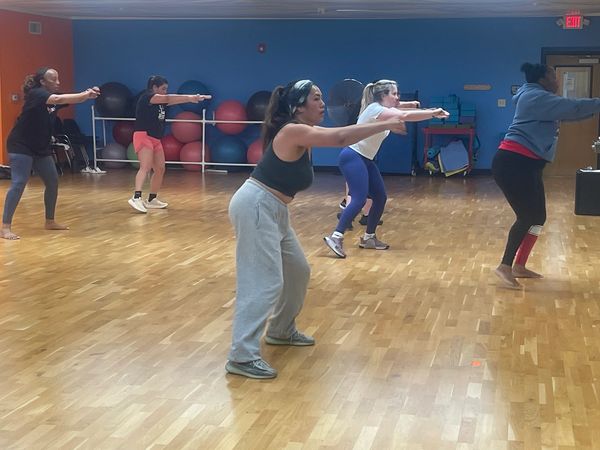 A group fitness class following instructor's guidance in a gym studio.