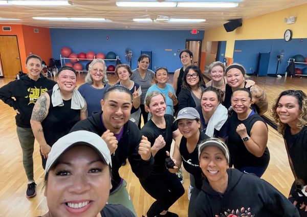 Group of people smiling and posing in a fitness studio after a workout.