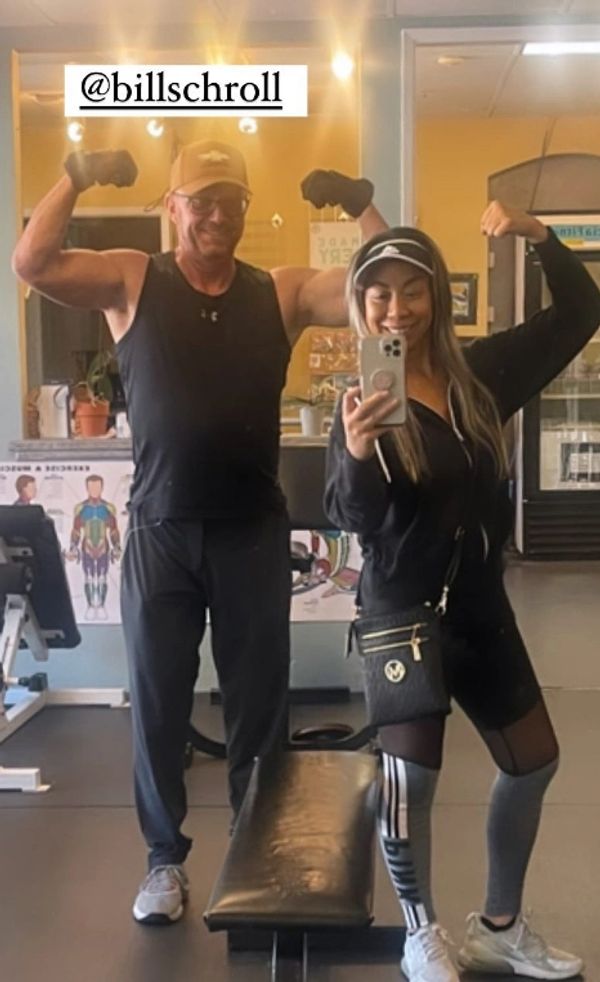 Two people flexing their muscles in a gym mirror selfie.