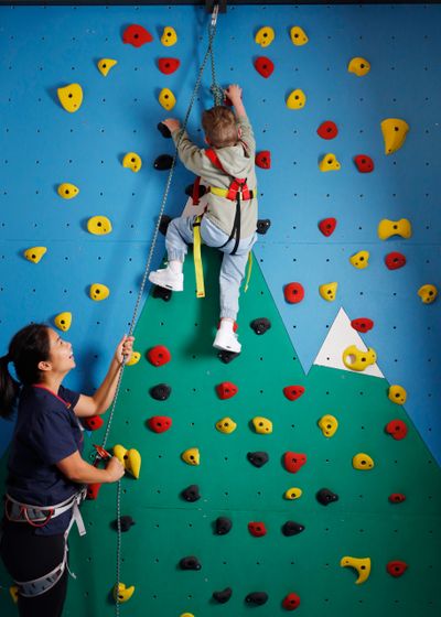 Child rock climbing with paediatric physiotherapist to improve gross motor skills and strength
