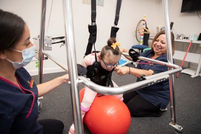 Kid in suspension walker assistive technology with paediatric and neurological physiotherapists