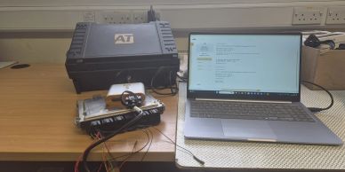 Laptop connected to automotive diagnostic equipment on a desk.