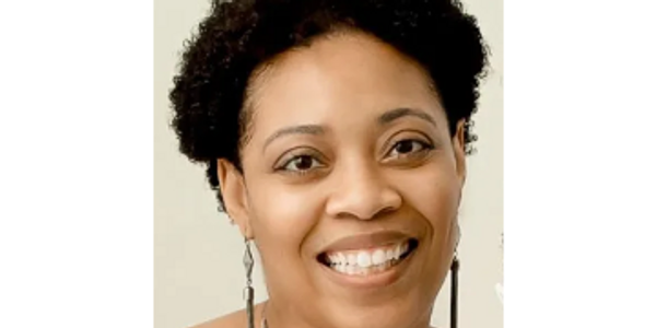 Smiling woman with curly hair and dangling earrings.