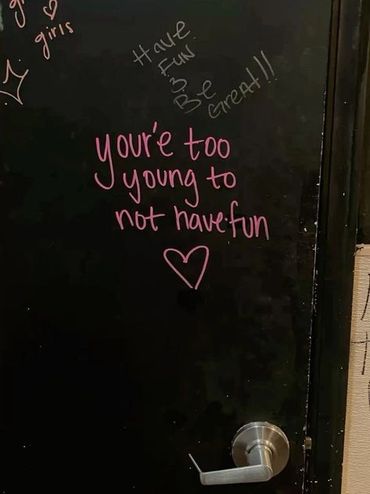 Inspirational message on a black door encouraging fun and youthfulness.