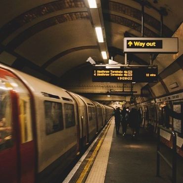 A subway train arrives at an underground station with passengers on the platform.