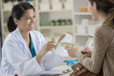 Pharmacist handing a prescription bag to a customer at Summerdale Pharmacy counter.