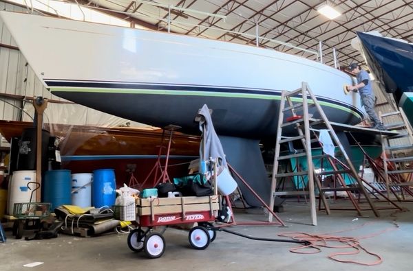 Worker polishing a boat inside a warehouse.