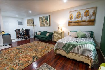 Clean room design with a forest green wall, plush bed, and sleek sofa.