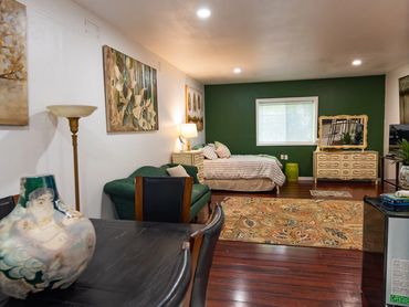 Rich green wall backdrop for a luxury bed and designer sofa arrangement.