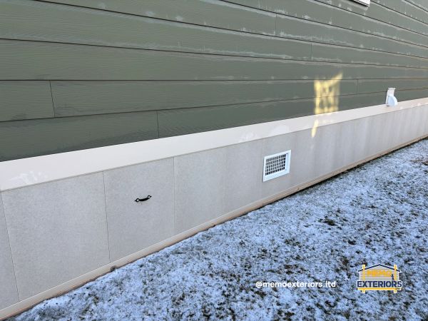 House exterior with green siding, vent, and snowy ground.
