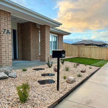 Modern brick house with minimalist garden and mailbox labeled 7A/7B.