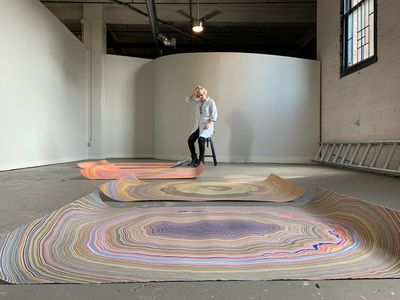 A woman away from three artworks on the floor