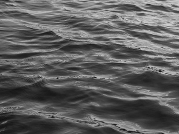 Black and white photo of water ripples on a body of water.