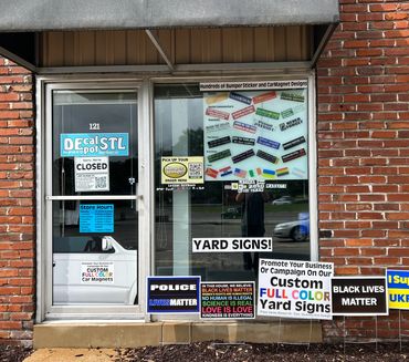 A closed storefront for Decal Spot STL with various bumper and car magnet stickers displayed.