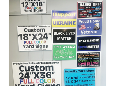 Various custom yard signs and messages supporting causes and services on a display wall.